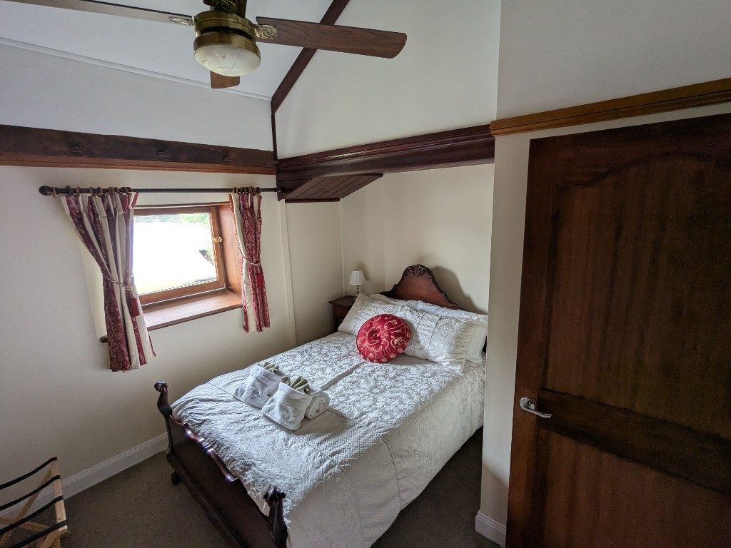 Double bedroom with carved timber bed and ceiling fan
