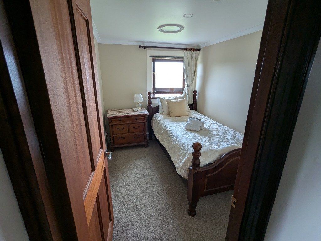 Single bedroom seen through the doorway, towels ready on the bed