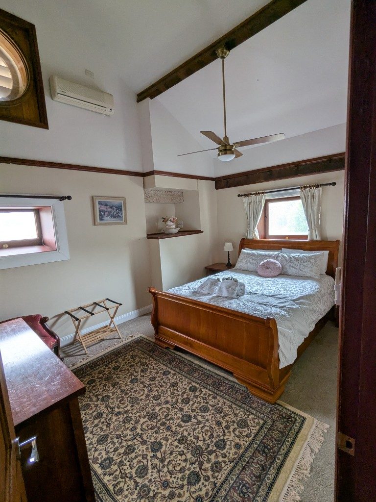 Queen bedroom with timber sleigh bed and oriental rug