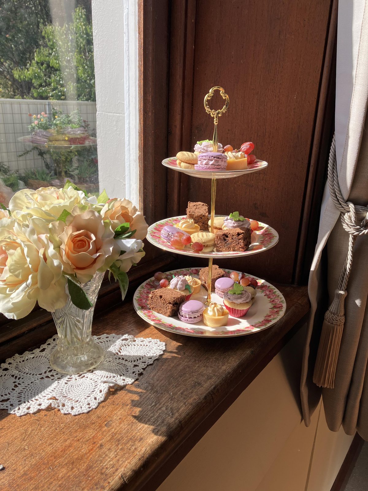 High tea stand with cakes, macarons and roses