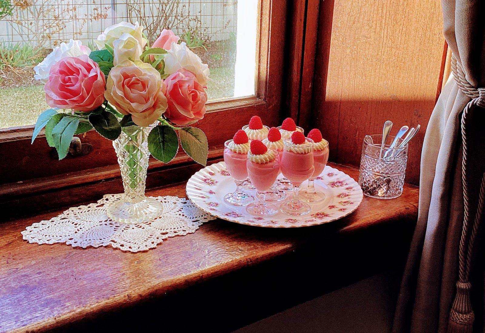 Raspberry desserts and roses on the windowsill