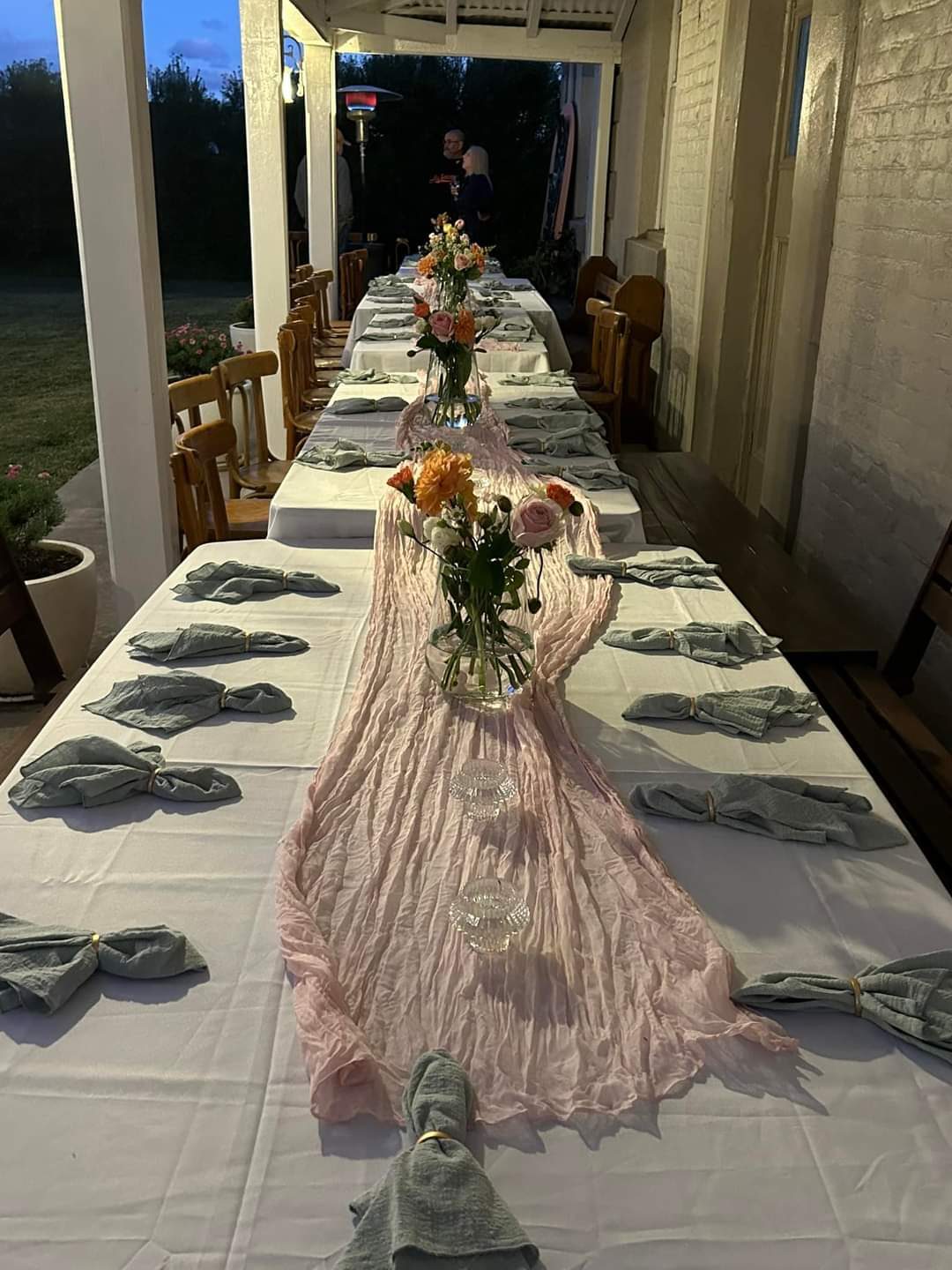 Long table set for an evening gathering on the verandah